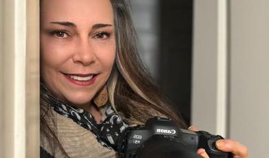 A woman smiling holding a camera 